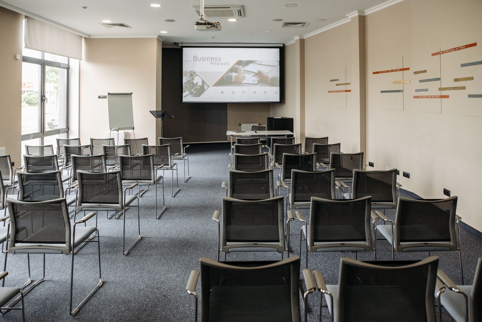 Prázdna konferenčná miestnosť so stoličkami, projektorom a premietanou prezentáciou